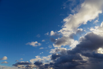 Obraz premium Cumulus gray-white clouds form a wavy pattern against the blue sky.