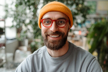 Portrait of smiling bearded man wearing glasses and yellow beanie looking at camera