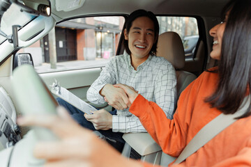 Driving instructor shaking hands with student after successful driving test