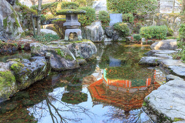 石灯籠と池に映った朱色の円堂