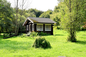 A beautiful Italian-style gazebo made of natural wood stands in a picturesque place in a clearing