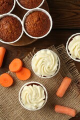 Tasty carrot muffins and fresh vegetables on wooden table, flat lay