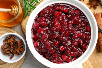 Tasty cranberry sauce in gravy boat, honey and spices on grey table, top view