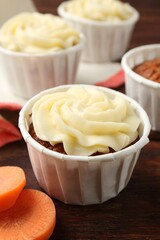 Delicious carrot muffins and fresh vegetable on wooden table, closeup