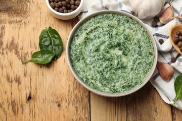 Delicious spinach sauce served on wooden table, flat lay