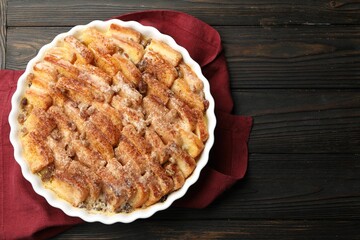 Delicious bread pudding with raisins and cinnamon on wooden table, top view. Space for text