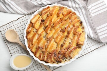 Delicious bread pudding with raisins and condensed milk on white table, flat lay