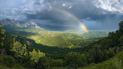 A stunning rainbow stretches across the sky, illuminating a lush green valley surrounded by towering mountains. Dark clouds gather, hinting at an imminent storm while sunlight breaks through