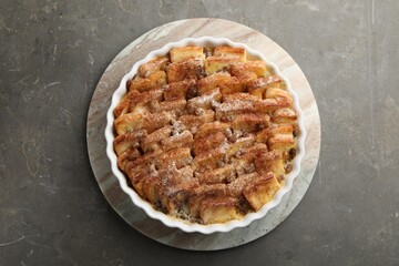 Delicious bread pudding with raisins and cinnamon on grey table, top view