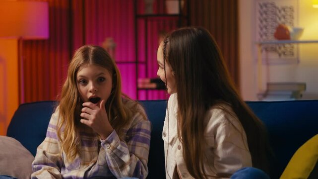 Teen girl shares an exciting secret with her friend, and they hug in celebration