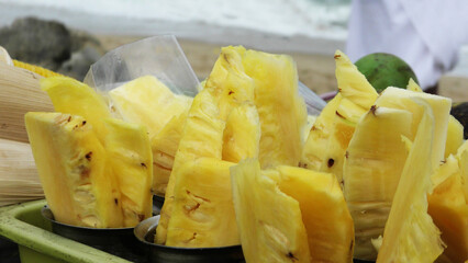 Sliced fresh pineapple fruit displayed at a street food stall