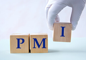 Cubes with the abbreviation PMI in the hand of a doctor.
