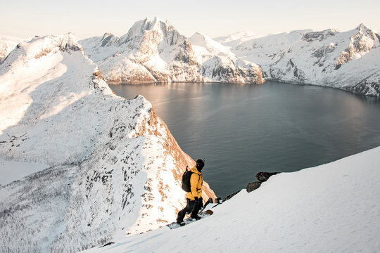 Splitboarder standing on his splitboard in the foreground and admiring the beauty of mountain range