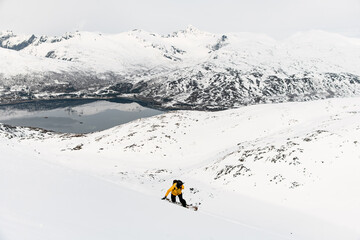 Top view of a slope on which an extreme one-armed skier in a yellow jacket completes a descent on a...