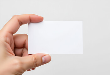Obraz premium A simple blank business card in hand on a plain light background. Blank form mockup. Business and services concept