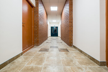 white empty long corridor with red brick walls and doors in interior of modern apartments or office