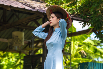 Young attractive Vietnamese woman in traditional Ao Dai costumes holding Vietnam hat