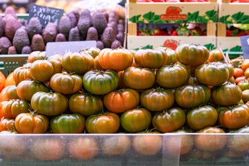 A vibrant pyramid of red and green tomatoes neatly arranged on a rustic farmer's market stall, showcasing the freshness and organic nature of the produce in a health-conscious setting
