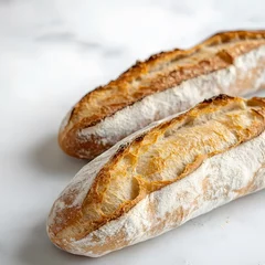 Selbstklebende Fototapeten Two loaves of bread on a white surface including a long crusty baguette and a soft roll isolated on a white background © Chamarn
