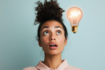 Portrait of a person with a surprised expression with a glowing lightbulb, brightly illuminated, representing a new idea.