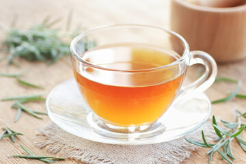Rosemary herbal tea in a glass cup with fresh leaves on wooden rustic background, closeup, immune, skin and hair healing drink, natural medicine and naturopathy concept