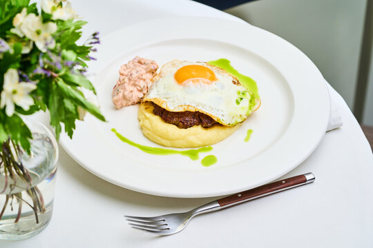 Steak and Eggs. The dish includes smooth creamy sides and a vibrant green sauce enhancing the visual appeal