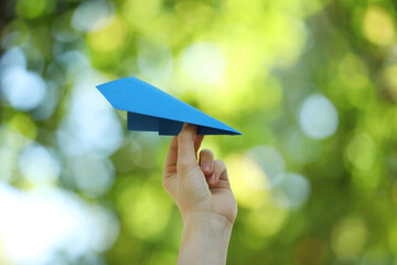 Woman with handmade paper plane on blurred green background, closeup