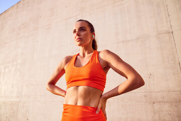 Low angle shot of athletic woman with earphones focusing before exercise outdoor