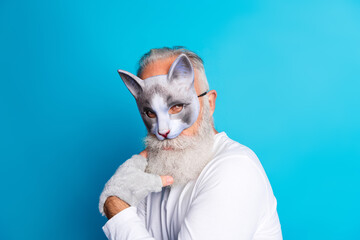 Elderly man wearing a cat mask with a vibrant blue background portraying cosplay and leisure