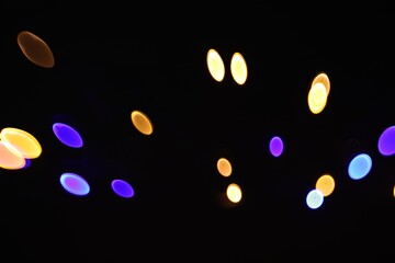Blurred view of colorful lights on black background, bokeh effect