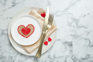 Romantic place setting for Valentine's day. Tableware, cutlery and decorative hearts on white marble table, top view. Space for text
