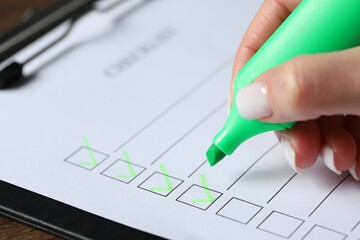 Woman checking box of paper form at table, closeup