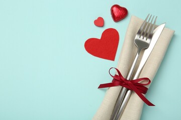 Valentine's day celebration. Romantic place setting with cutlery and hearts on light blue background, flat lay. Space for text
