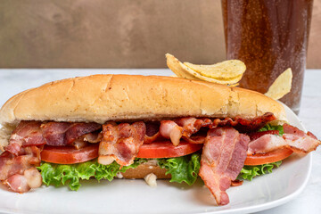 blt sub  served with a soft drink and chips