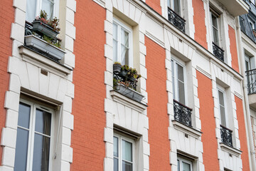 Naklejka premium Charming urban facade showcasing colorful flowers in balcony pots