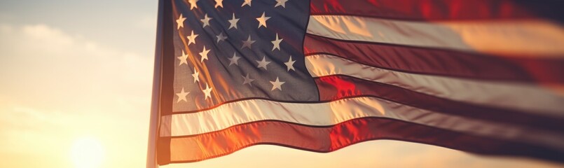 The American flag waves proudly against a backdrop of a stunning sunset, filling the sky with warm hues while illuminating the surrounding landscape.