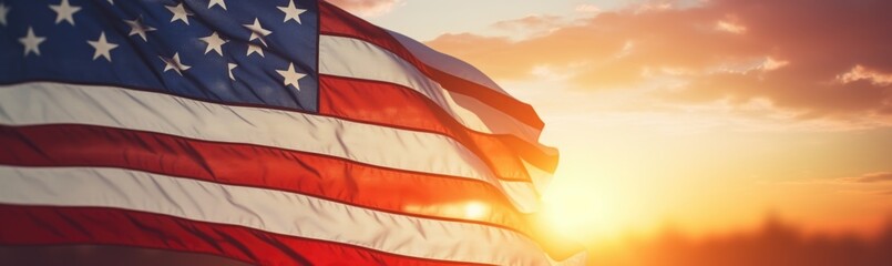 The American flag waves proudly against a backdrop of a stunning sunset, filling the sky with warm hues while illuminating the surrounding landscape.