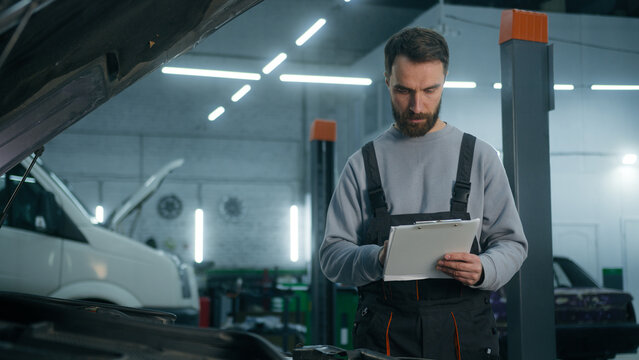 Professional auto mechanic vehicle engineer man checking car maintenance at service station inspect automobile transport repair male mechanical worker repairman in uniform control automotive condition