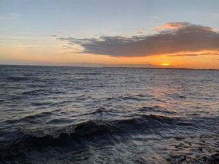 A beautiful sunset paints the ocean horizon with vibrant orange and red hues