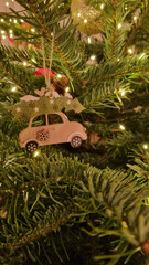 Christmas tree toy close-up. Christmas tree decoration and arrangement. LED lights and a wooden toy hanging on a branch.