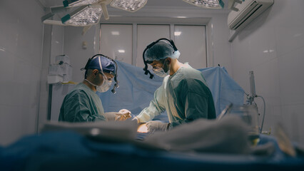 Team of two doctors men surgeons processing surgical operation using endoscopic medical instruments...