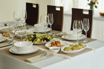Elegant dining table with dishes and empty wineglasses serving for banquet