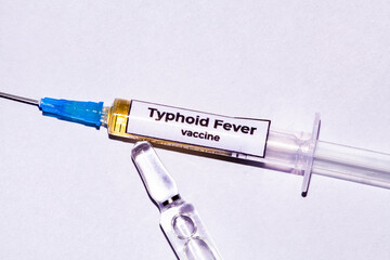Picture on a white background with a syringe full of typhoid fever virus vaccines, and next to it...