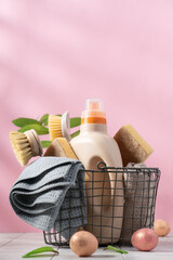 Basket with spring cleaning tools on pink background surrounded by decorative easter eggs. Easter eco cleaning concept background