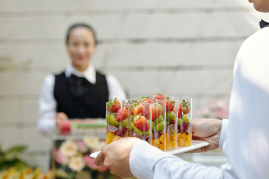 Close-up of person serving fruits in glass during catering service