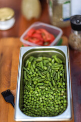 Cooking a healthy vegetarian dish. A metal bowl with fresh green peas on a wooden table. Ingredients for a delicious lunch.