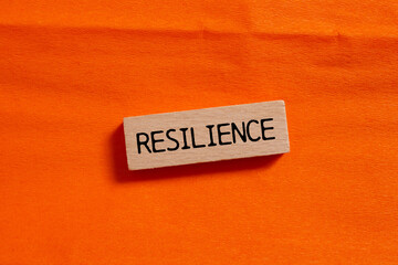 Resilience message written on wooden block on orange background. Conceptual resilience symbol. Copy space.