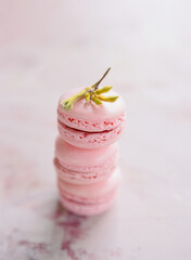Delicious pink macarons stacked with floral decoration on a pale background at a pastry shop
