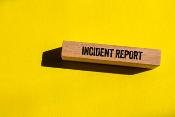 Incident report message written on wooden block on yellow background. Conceptual incident report symbol. Copy space.