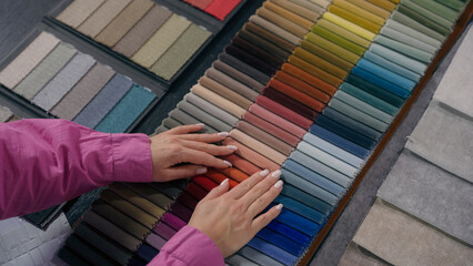 Unrecognizable woman girl hands customer stroking textile samples velvet fiber cloth choosing buying shopping colorful palette female fashion designer tailor arms choose decor in fabric store atelier